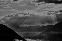 a black and white photo of mountains with sun rays